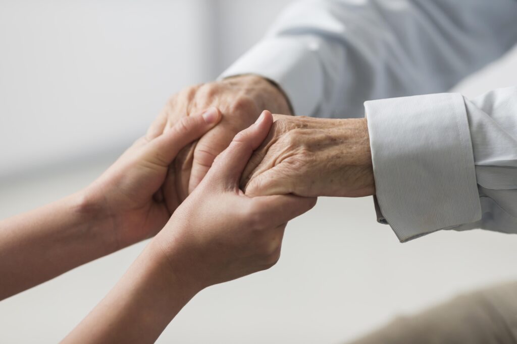 Krankenschwester hält die Hände eines älteren Mannes
